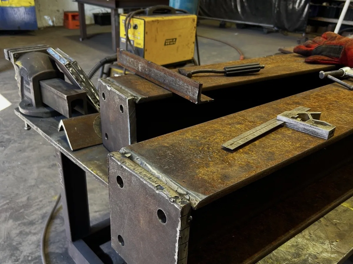Steel components and welder on a workshop bench
